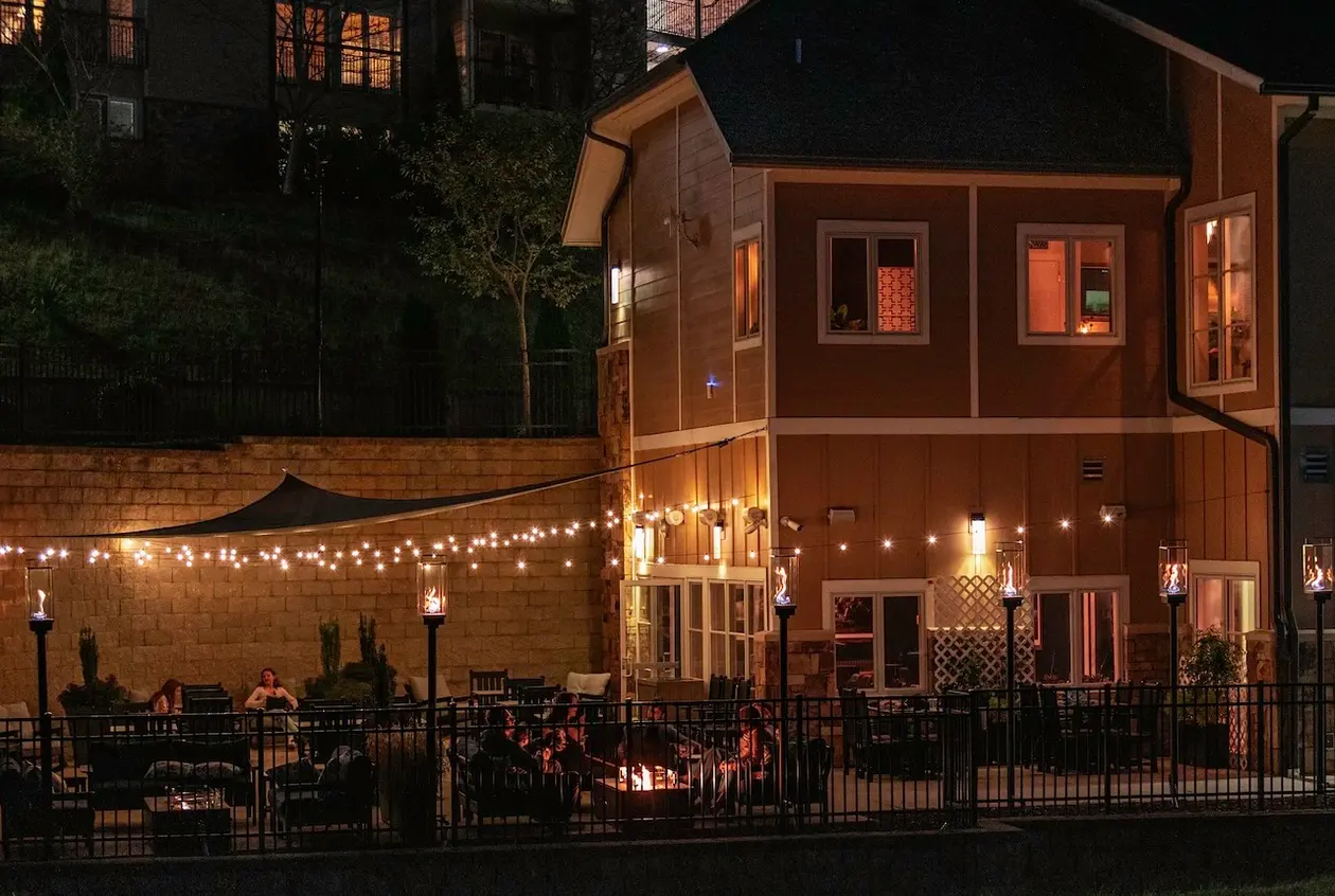 Two people holding drinks and talking on the patio during sunset.